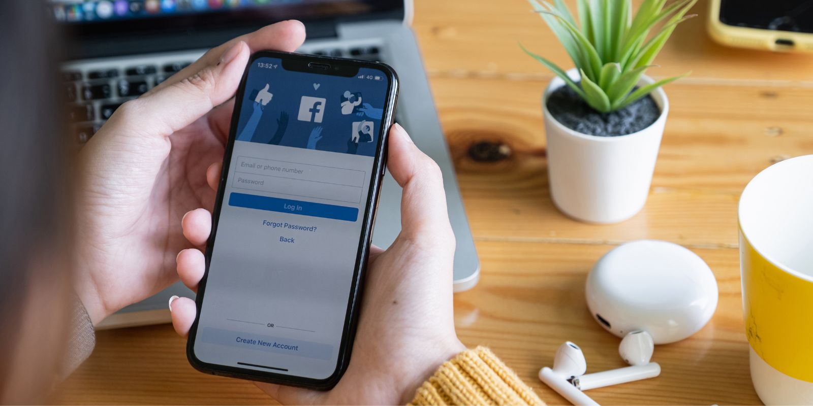 FanPage na tle wyświetlacza telefonu trzymanego w ręce.